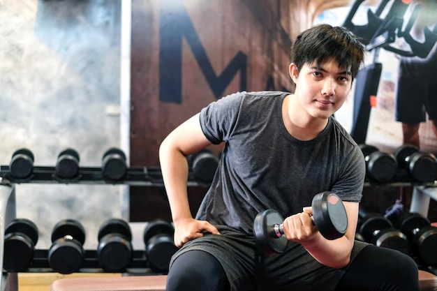 Asian man exercising using dumbbell in the gym