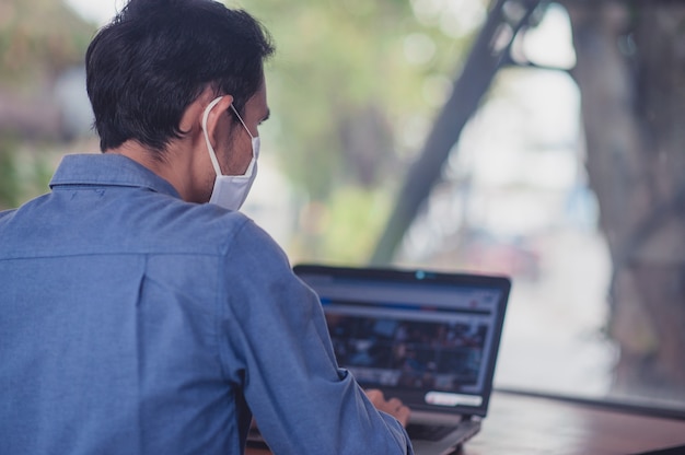 Asian man in face mask work in office concept working new normal social distancing