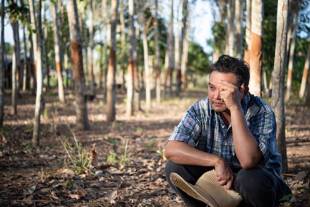 Agricoltore agricoltore uomo asiatico infelice dalla bassa produttività di rendimento alla piantagione di alberi della gomma