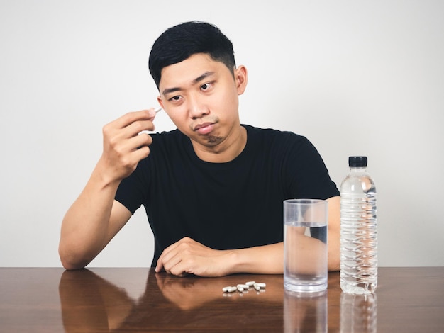 Asian man feels bored hold pill and waterMan scared to eat medicine