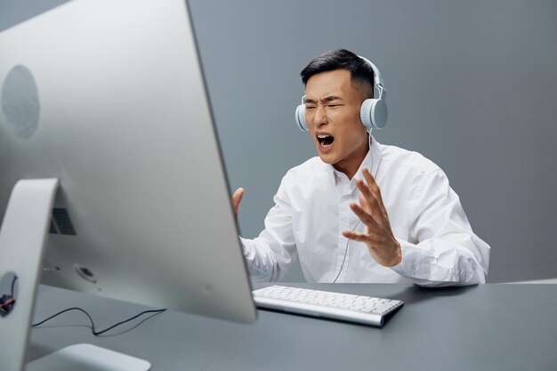 Asian man in front of the computer with headphones emotions\
isolated background