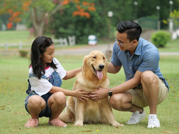 Asian man and girl with dog golden retriever in park