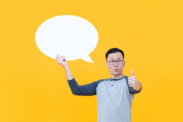 Asian man giving thumbs up while holding blank speech bubble