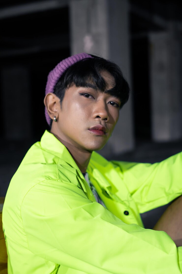 Photo 녹색 재킷을 입은 동양인 남자가 아주 자연스럽게 포즈를 취하고 앉아 있다