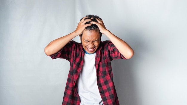 Asian man hitting his head suffering from migraine headache or regret gesture against white background