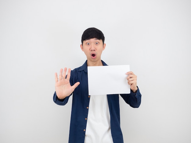Uomo asiatico che tiene un foglio bianco e mostra la mano alzata dire no faccia seria su sfondo bianco isolato,