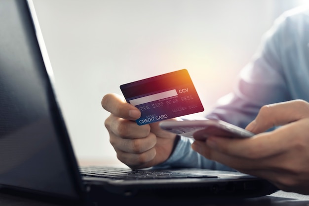 Азиатский мужчина, держащий кредитную карту, делает онлайн-платеж после покупки в Интернете