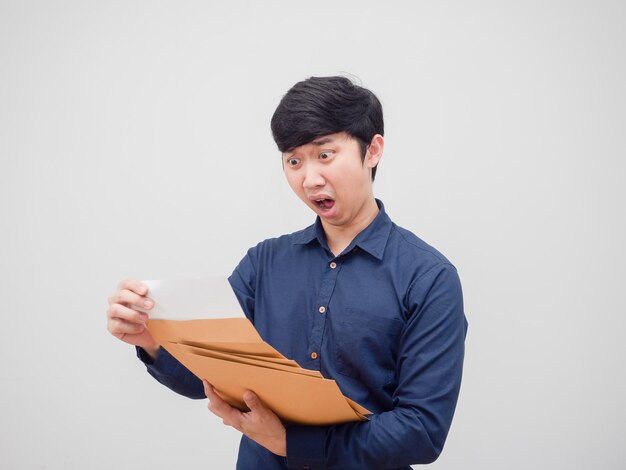 Asian man holding document envelope and reading the paper in hand feeling shocked white background