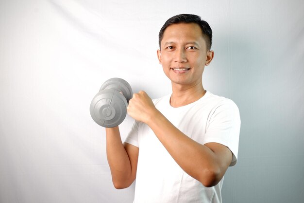 Asian man holding a Dumble and clenching fist isolated on white background