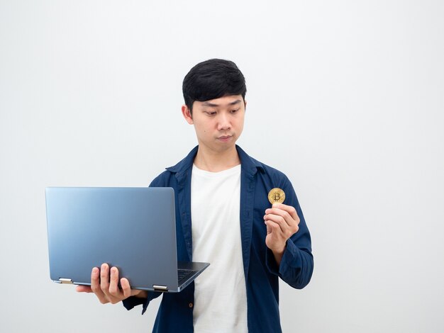 Asian man holding laptop and looking at bitcoin in hand on white background digital money concept