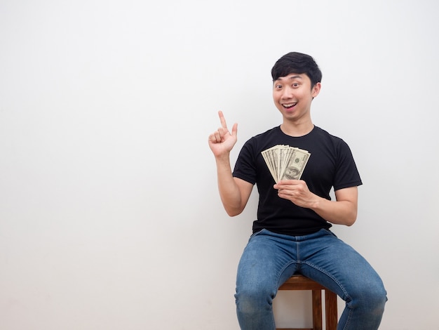 Asian man holding money in hand and point finger at copy space cheerful and happy smile rich man concept