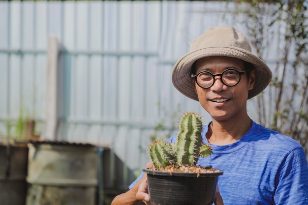 Uomo asiatico che tiene un vaso di pianta di eufobia con felicità