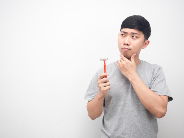 Asian man holding shaving gesture thinking and looking at copy space