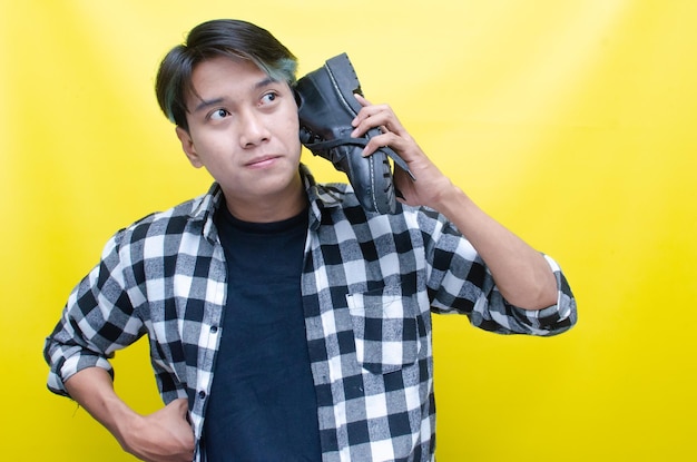 an Asian man holding shoes and using it as a phone shopping from home concept