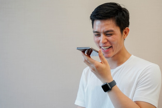 asian man holding smartphone to talking by voice recognition