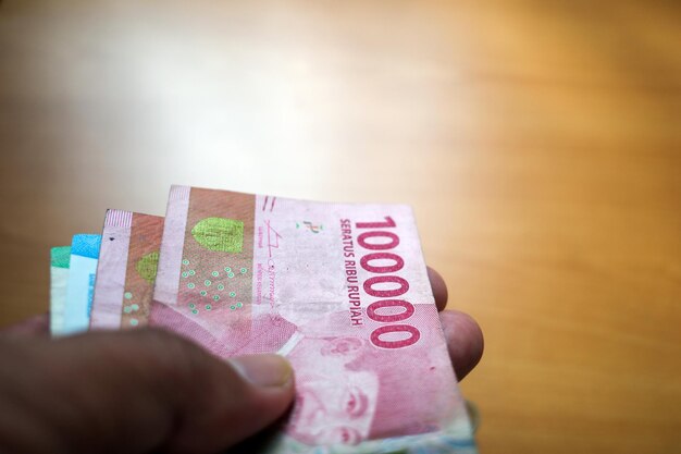 An Asian man holds Indonesian money in shallow focus Saving and giving concept