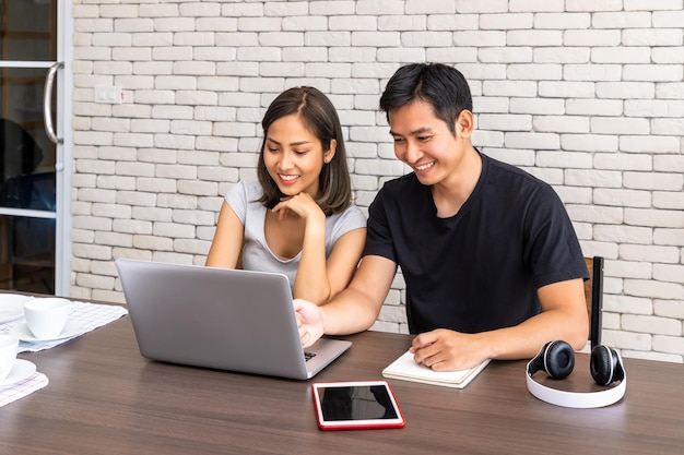 Asian man husband motivate advice wife woman freelancer working at home sitting at desk dining table in living room