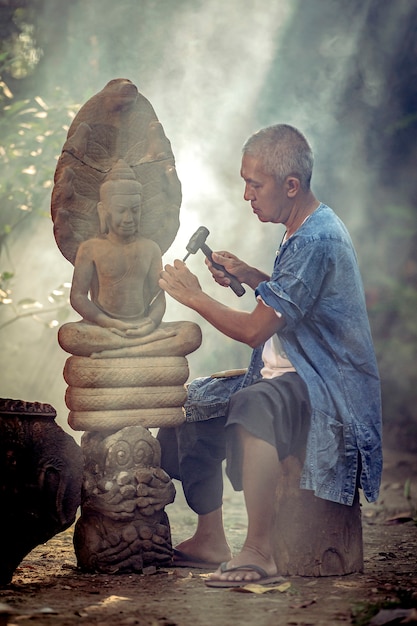 Asian man is carved stone into a Buddha image Ayutthaya Thailand