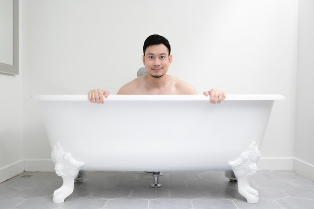 Asian man is having a good time in a white bathtub.