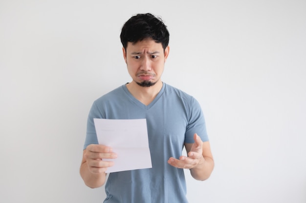 Asian man is sad and shocked by the letter in his hand on isolated background.