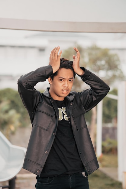 An Asian man is standing beside a cafe table in black leather clothes