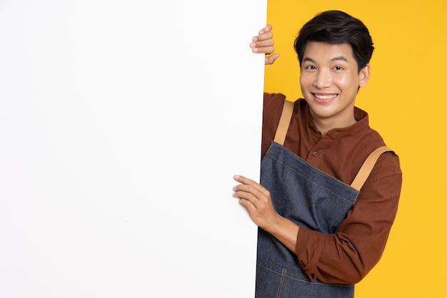 Asian man is standing behind the white blank banner on yellow background