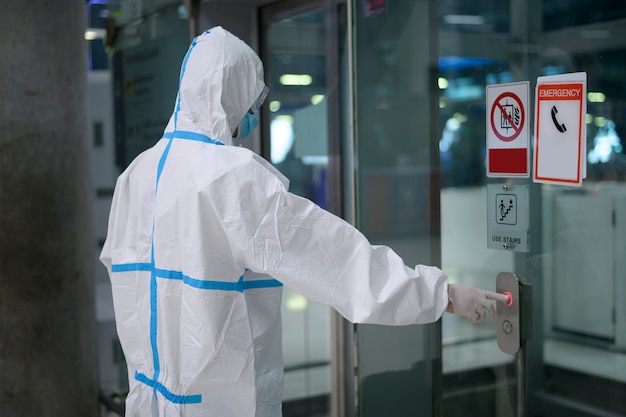 An Asian man is wearing ppe suit in airport elevator , Safety travel , covid-19 protection , social distancing concept