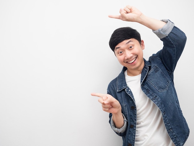 Asian man jeans shirt smiling gesture pointing finger at copy space