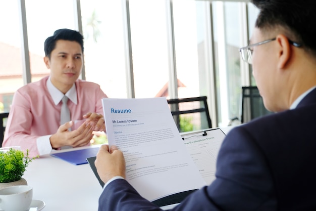 Uomo asiatico nell'intervista di lavoro al fondo dell'ufficio, ricerca di lavoro, concetto di affari