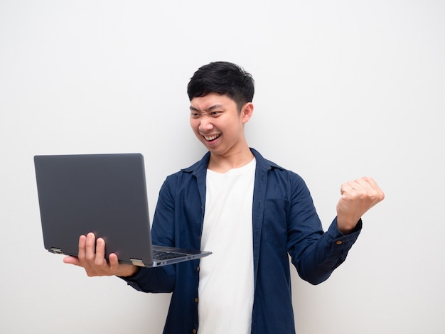 Asian man look at laptop in hand and feel happy show fist up happy smile on white isolated