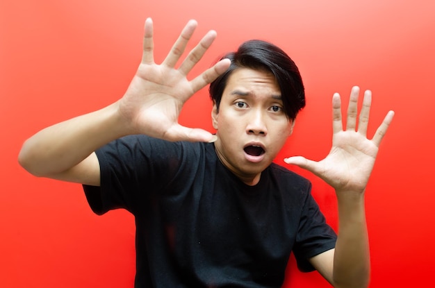 asian man making frightened gestures with his palms as if trying to defend himself from someone