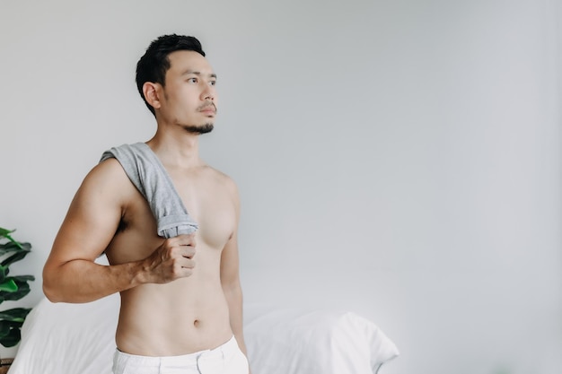 사진 윗옷을 입지 않은 아시아 남자는 자신의 아파트 거실에서 목욕 후 휴식을 취합니다.