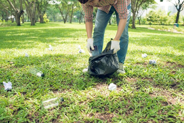 公園でプラスチックの家庭ごみを拾うアジア人男性