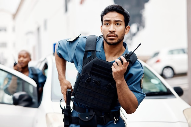 Asian man police and walkie talkie with gun in city for suspect communication or reinforcements Serious male person security guard or cop radio calling backup for crime in street of an urban town