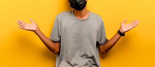 Asian man preventing coronavirus covid-19. Man wearing black mask. prevent infection airway disease virus protection concept yellow backdrop