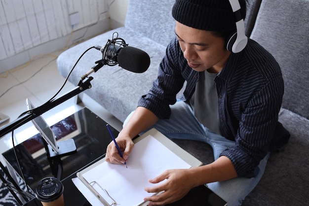 Asian man radio program host or blogger in headphones recording
audio podcast using professional equ