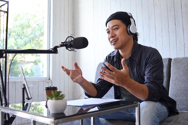 Asian man recording a podcast with headphone and microphone. Podcaster making audio podcast from hom