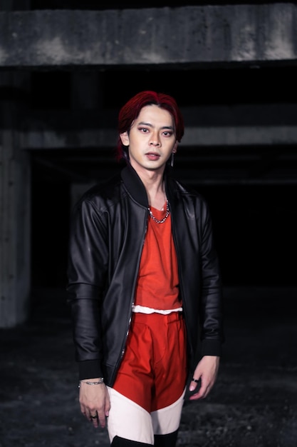 Азиатский мужчина в красной рубашке и черной куртке позирует руками