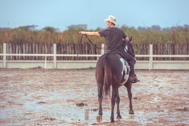 Asian man riding a horse at a farm