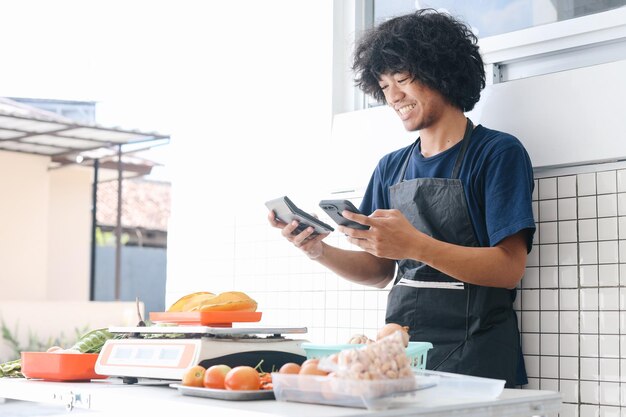 Foto venditore asiatico con smartphone e calcolatrice calcola le finanze del bilancio e effettua il pagamento su smart