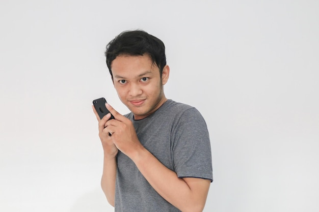 Asian man serious face and sharp looking with hiding the phone gesture isolated grey background