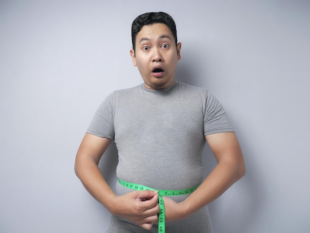 写真 アジア人男性がショックを受け 腹の大きさを測るときに心配し 肥満の問題の概念