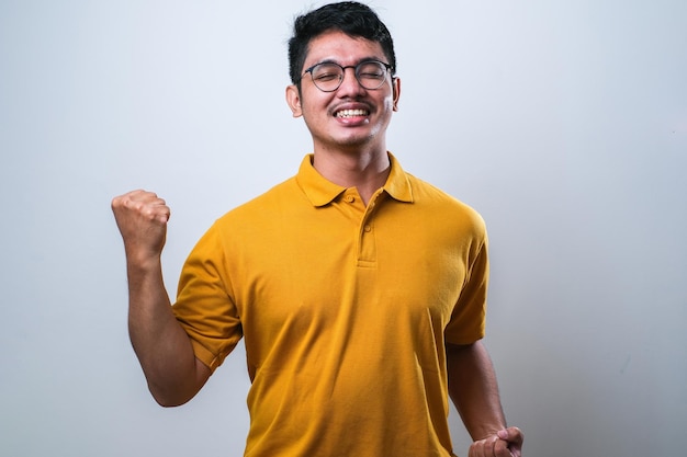 Asian man showing happy excited expression with clenched fist over white background