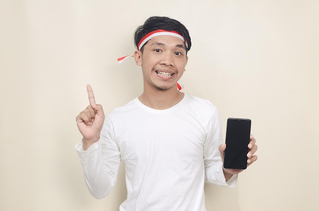 Asian man showing smartphone screen very happy pointing with hand and finger sideways the concept of independence