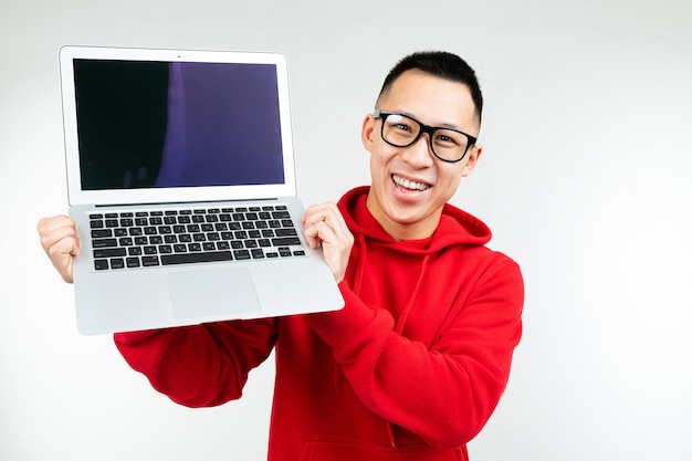 Asian man shows laptop screen with mockup on white studio background