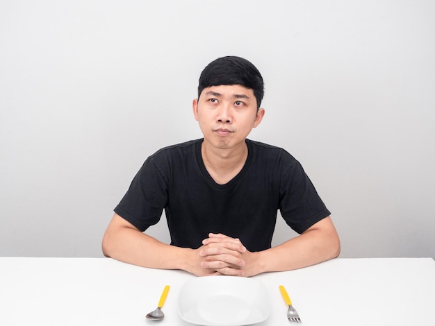 アジア人男性は食べ物について考えてテーブルに座っています