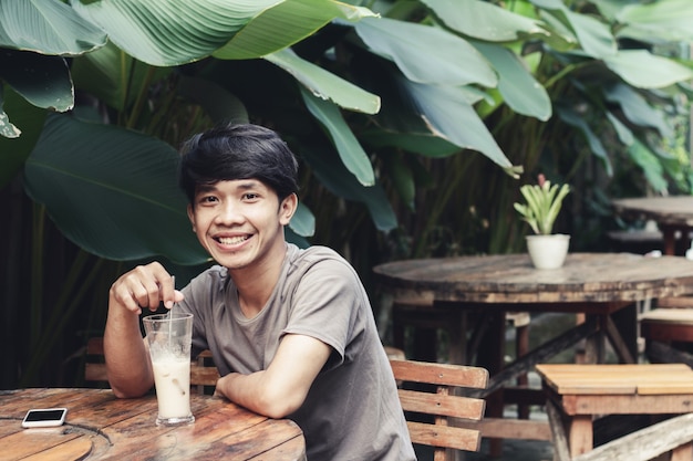 Asian man sitting in coffee shop drinking coffee