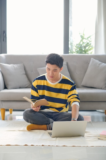 Asian man sitting on the floor and making making financial calculations online business in new apartment