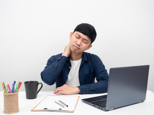 Uomo asiatico che si siede al concetto di sindrome dell'ufficio del dolore al collo del posto di lavoro dell'ufficio