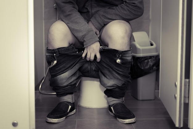 写真 トイレに座っているアジア人男性待つのは辛いdefecation